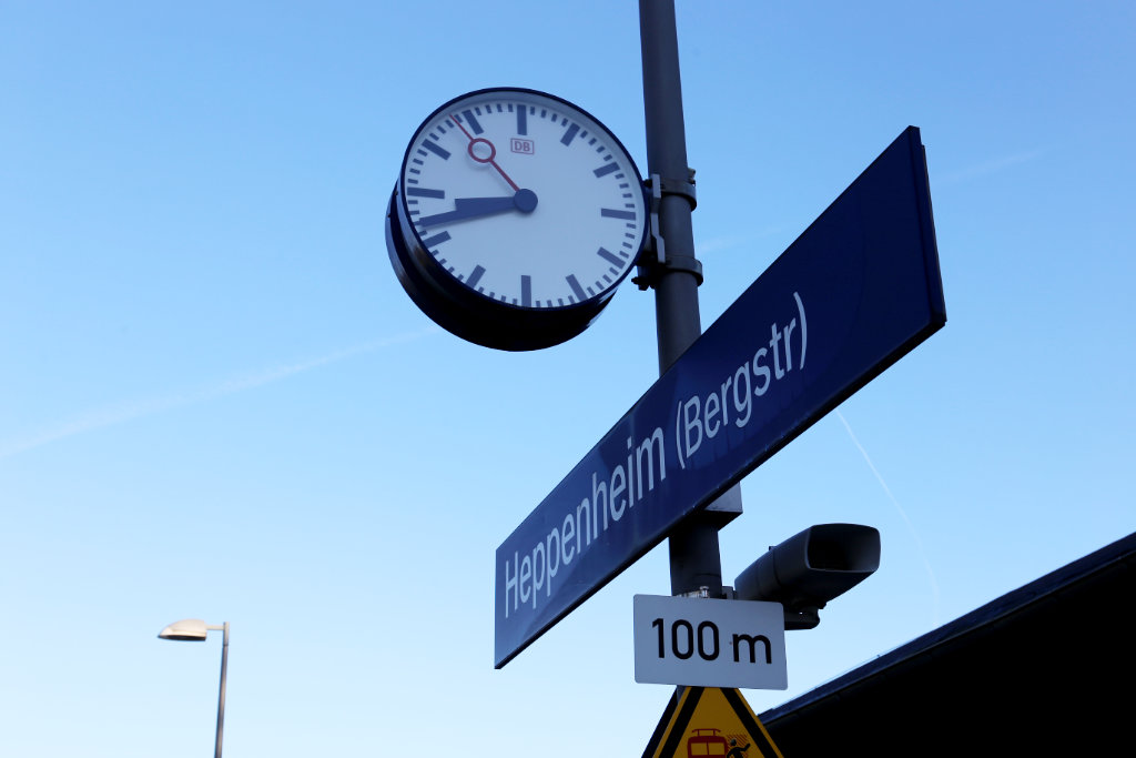 Schild mit Schriftzuge Heppenheim (Bergstr) am Bahnhof in Heppenheim und analoge Bahnhofsuhr