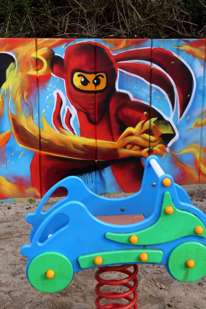 Spielplatz-Graffiti mit rotem Ninja und Schaukelauto