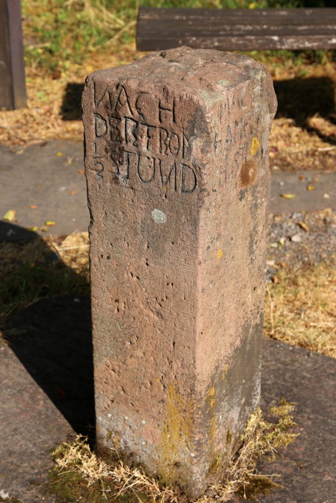 Alte Wegmarkierung mit quadratischem Grundriss, aus Sandstein, etwa 70 cm hoch, Aufschrift: Nach der Trom