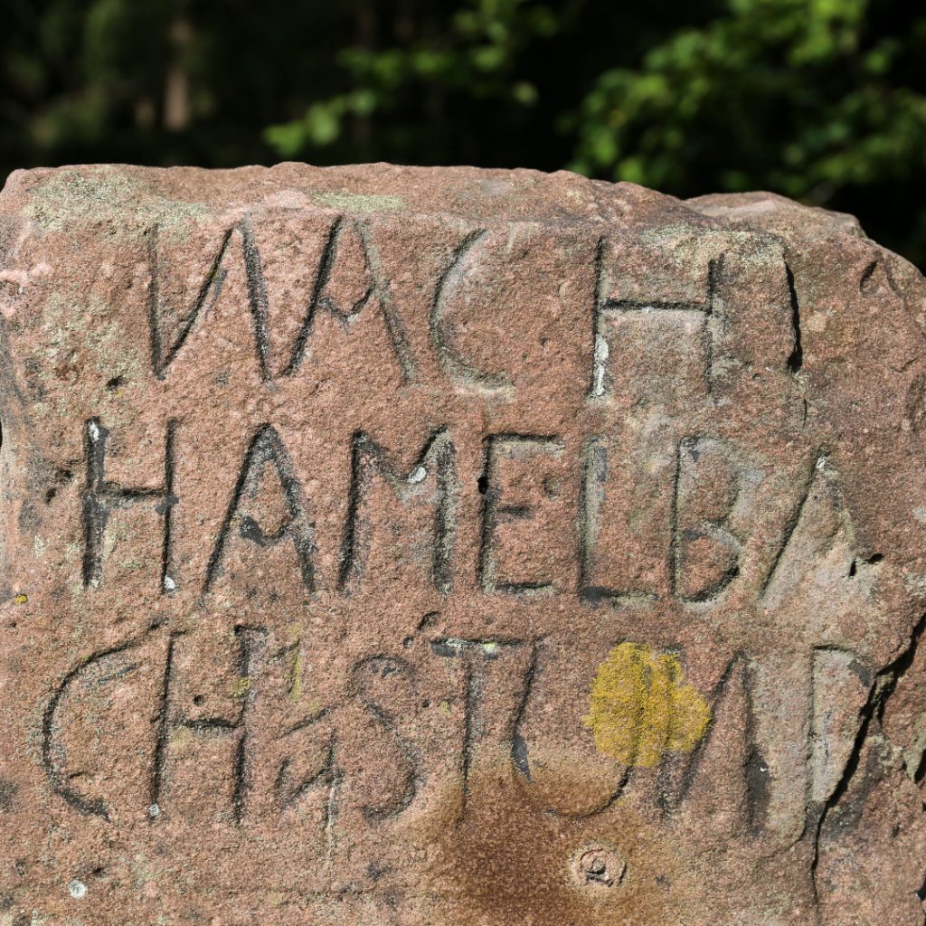 Ausschnitt aus einer alten Wegmarkierung aus Sandstein mit der Aufschrift: Nach Hamelbach
