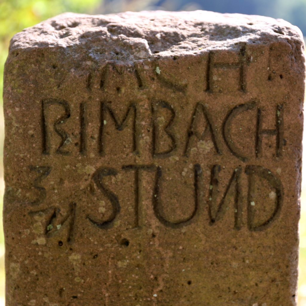 Ausschnitt aus einer alten Wegmarkierung aus Sandstein mit der Aufschrift: Nach Rimbach