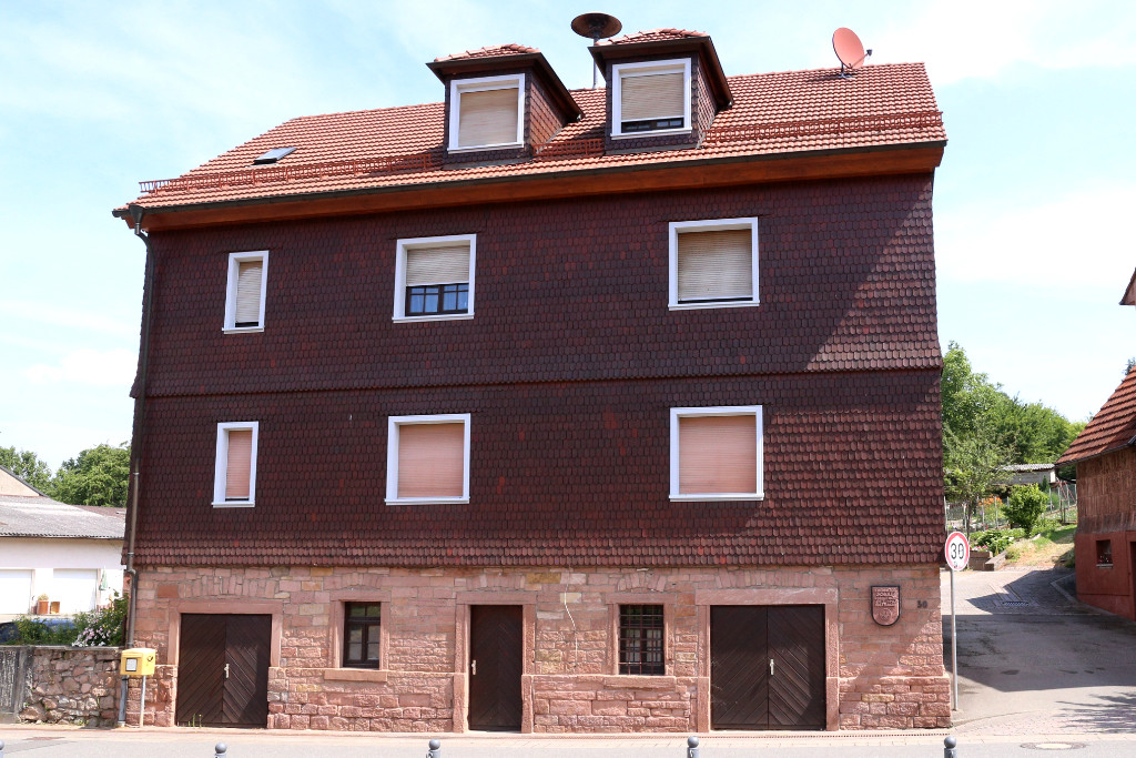 Dreistöckiges Haus mit Schindeln und rotem Sandstein im Erdgeschoss