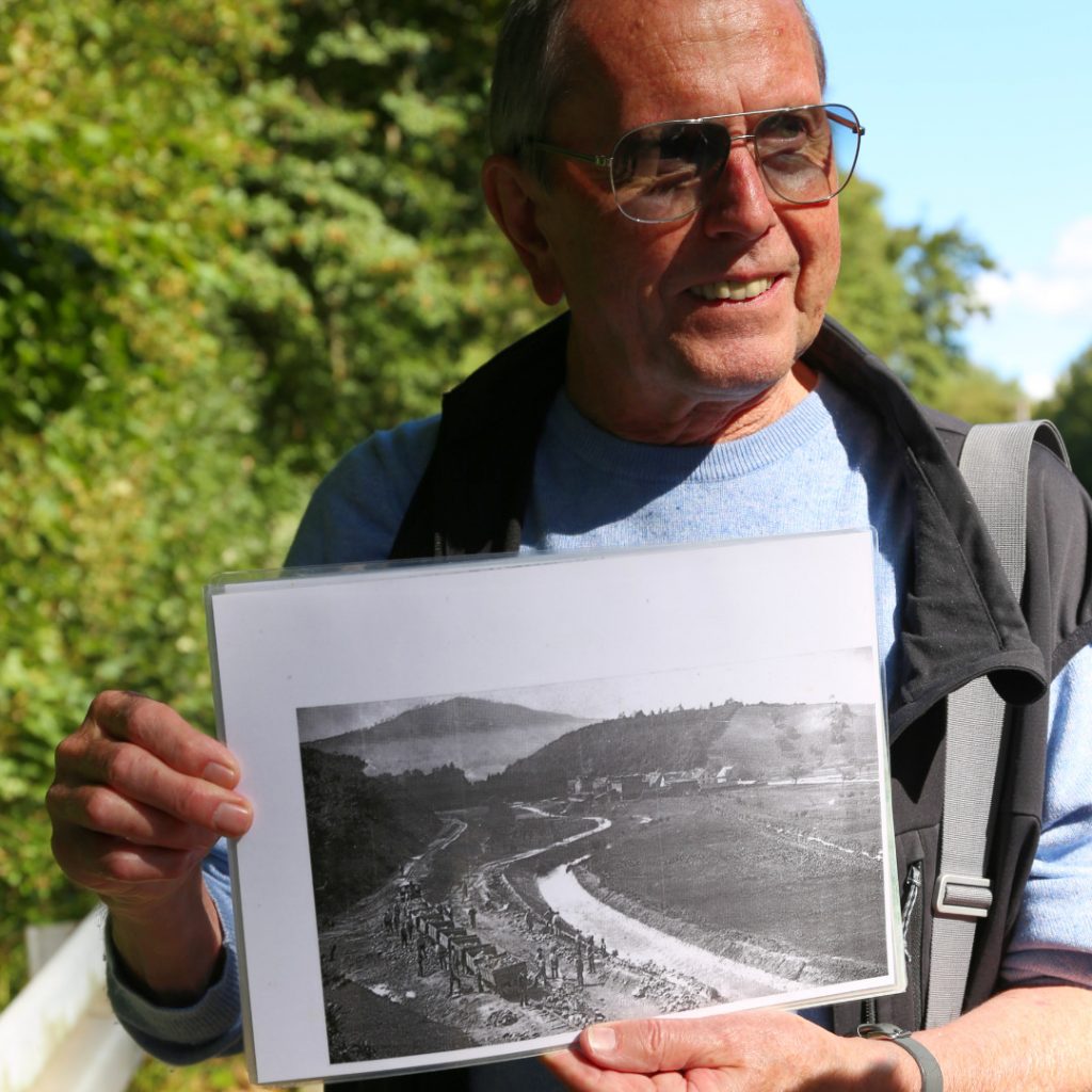 Mann zeigt Fotografie, die den Bau einer Eisenbahnlinie zeigt.
